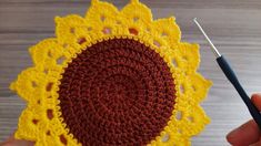 someone crocheting a sunflower in yellow and brown