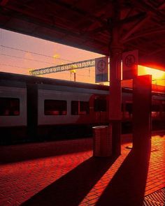 the sun is setting at an empty train station