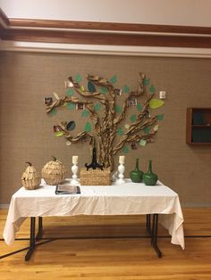 a table topped with vases and a tree cut out of wood on top of a white table cloth