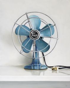 a blue fan sitting on top of a white shelf