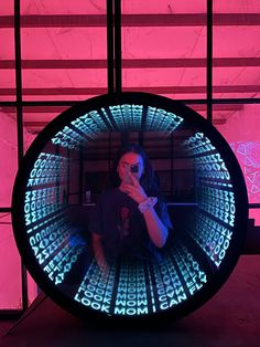 a woman taking a selfie in front of a mirror with neon letters on it