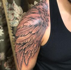 a man wearing a black tank top with an angel wing tattoo on his arm