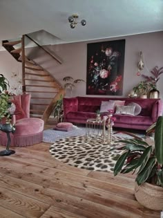 a living room filled with pink furniture and lots of plants on top of it's hard wood flooring