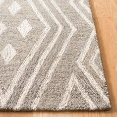 a gray and white area rug on a wooden floor with wood floors in the background