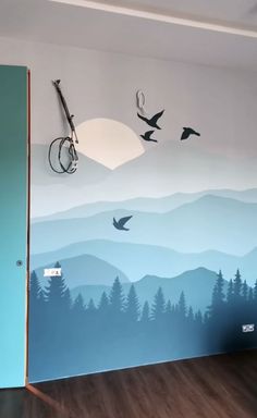 a room with mountains, birds and trees painted on the wall next to an open door