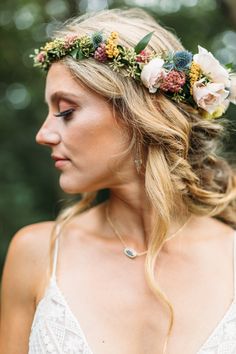 a woman with flowers in her hair wearing a floral headpiece on her wedding day