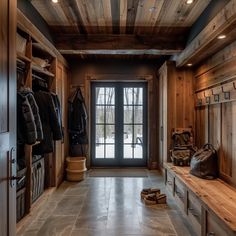 an entry way with wooden walls and doors leading to the front door is lit by recessed lights