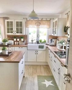 a kitchen filled with lots of white cabinets and counter top space next to a window