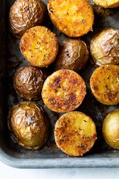 baked potatoes in a baking pan with seasoning sprinkled on the top and sides