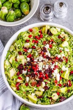 brussels sprouts salad with apples and cranberries in a white bowl on a gray table