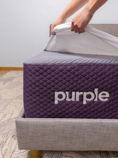 a person unpacking a purple mattress on top of a gray bed frame with the word purple printed on it