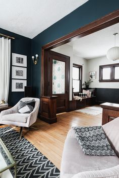 a living room with blue walls and white furniture in the center, along with wood flooring