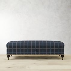 an upholstered bench with wooden legs and plaid fabric