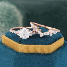 two wedding rings on top of a blue velvet hat with gold band and diamond accents