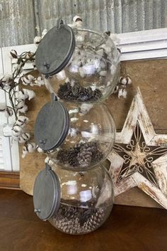 three clear glass jars filled with pine cones and other items