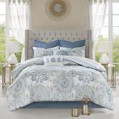 a bed with blue and white comforters in a room next to two nightstands