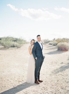 a man and woman are standing in the desert together, posing for a photo with their arms around each other