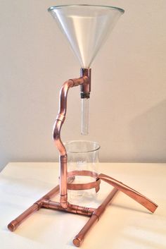 a copper colored coffee maker with a clear glass on it's base and wooden legs