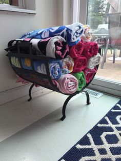 a stack of folded towels sitting on top of a metal rack next to a window