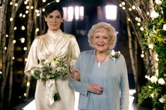 two women standing next to each other in front of a archway with lights on it