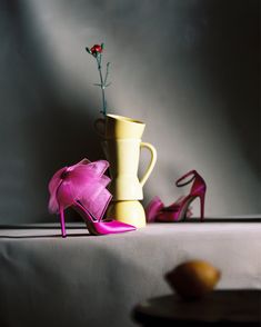 a vase with a flower in it next to high heel shoes