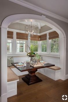 an archway leading into a dining room with a table and bench in the center area