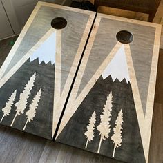 two cornhole boards with trees painted on them sitting on the floor in front of a door