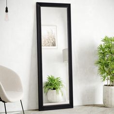 a large mirror sitting next to a potted plant on top of a white floor