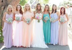 a group of women standing next to each other in long dresses and holding bouquets