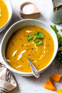 two bowls filled with soup and garnished with cilantro on the side