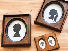 three framed silhouettes of people in different frames on a wooden table with flowers and leaves