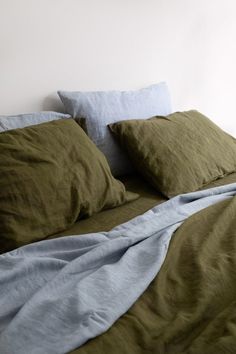 an unmade bed with green and blue linens on the comforter is shown