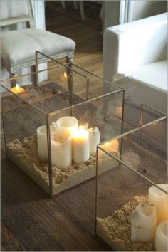 candles are lit in glass containers with sand on the floor next to them and placed inside one another