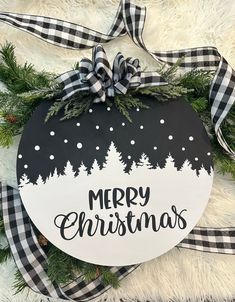 a merry christmas ornament hanging from a wreath on top of a fur rug