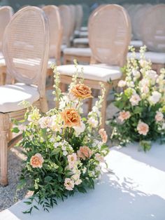 the chairs are lined up with flowers in vases next to each other on the ground