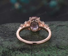 a pink diamond ring sitting on top of a rock