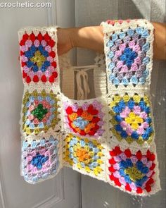 a crocheted bag hanging from the side of a door with flowers on it