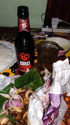 a table topped with lots of food next to a bottle of booze and rice