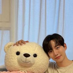 a young man poses with a large teddy bear