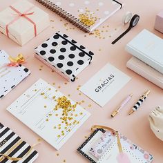 various stationery items laid out on a pink surface, including notebooks and pens