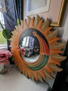 a mirror sitting on top of a table next to a vase filled with flowers