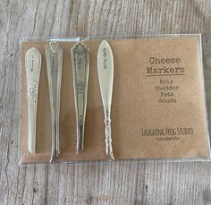 three silver cheese knives sitting on top of a piece of paper next to each other