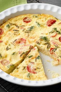 an omelet with tomatoes and herbs in a white dish on a wire rack