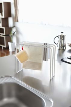 a kitchen counter with a sink and dish drying rack on it, next to a coffee pot