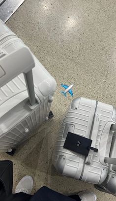 two pieces of luggage sitting on top of a floor next to each other with an airplane in the background