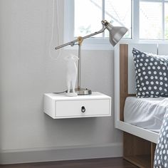 a white cat figurine sitting on top of a nightstand next to a bed