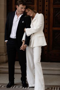 a man and woman standing next to each other in front of a door holding hands