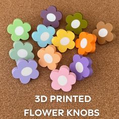 3d printed flower knobs are shown in different colors and sizes on a cork board