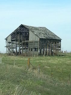 an old wooden barn sitting on top of a lush green field