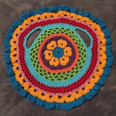 a multicolored crocheted doily with flowers on the center and bottom